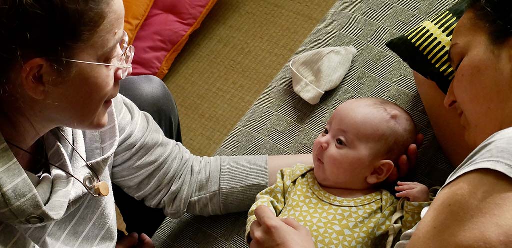 In this photo, a tender and soothing moment is shared between a therapist, a mother, and her baby during a biodynamic craniosacral therapy session.
The baby is lying on its back, comfortably settled, gazing at the therapist with curiosity and calmness. The mother, lying beside the baby, gently holds its head, creating a cocoon of safety and softness.
The therapist, seated nearby, observes the scene with care and compassion, emphasizing the importance of connection and attentive listening in this type of therapy. The cozy setting, with cushions and soft textures, reinforces the sense of warmth and security.
This image beautifully illustrates how craniosacral therapy supports babies and their parents by promoting emotional balance, easing tension, and fostering a sense of inner safety from the earliest stages of life.