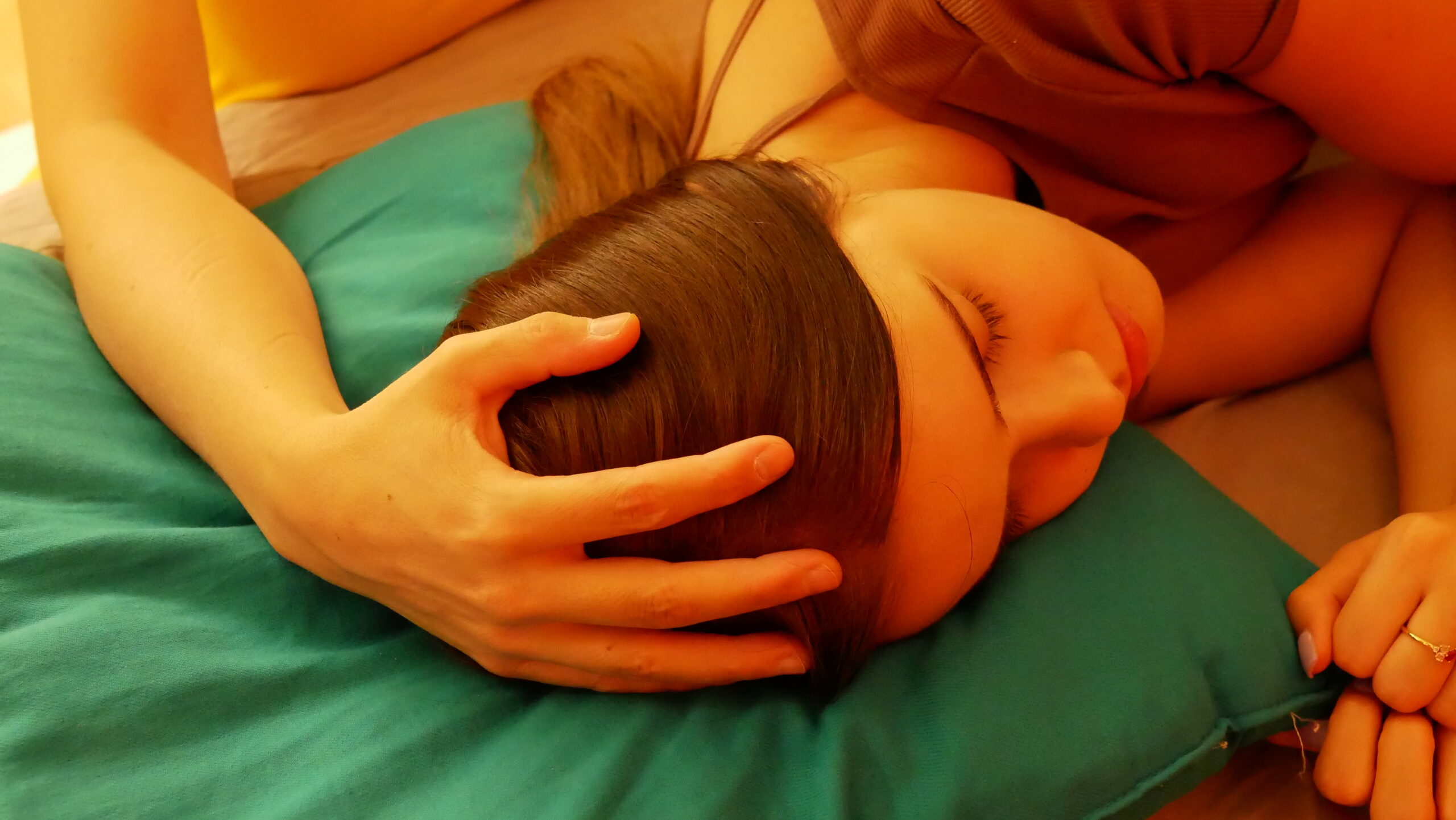 In this photo, a moment of deep relaxation during a biodynamic craniosacral therapy session is depicted.
A woman is lying on her side, her head resting on a blue cushion. Her eyes are closed, and her face reflects a state of calm and release. A hand gently placed on her head demonstrates the soft and attentive approach characteristic of craniosacral therapy.
The therapist’s centered and present posture conveys a sense of respectful and reassuring support, promoting nervous system balance and encouraging the body’s self-regulation.
This image captures the serenity and sense of safety sought during craniosacral therapy, highlighting the importance of mindful touch and body awareness in this gentle manual therapy.